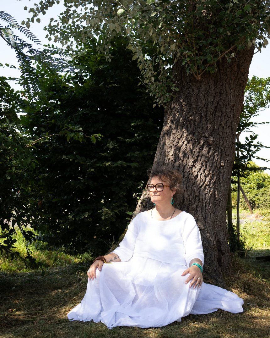 Laurence, fondatrice des Soins en Couleurs, assise au pied d'un arbre dans les Landes